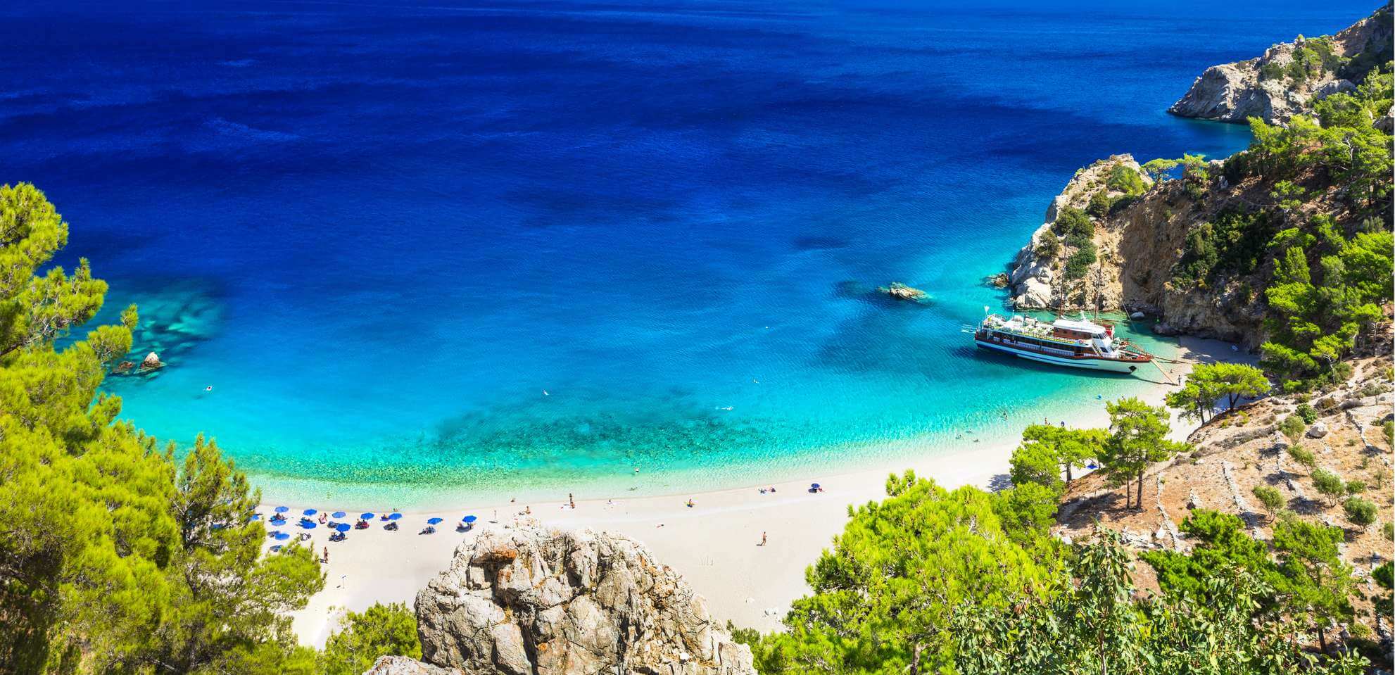 Spiaggia delle Isole Canarie con rocce, alberi e nave